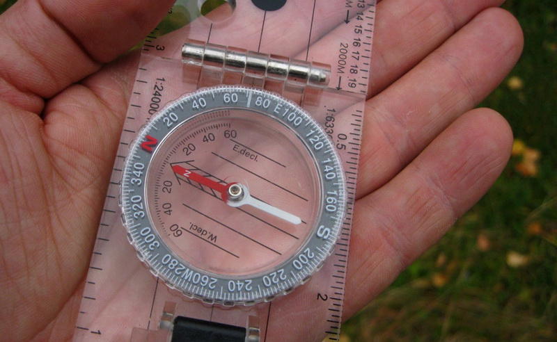 Где тут чтоВ первую очередь, необходимо просто разобраться, из чего состоит компас. Можно, конечно, обойтись и без этого, но будет сложнее пользоваться - зачем?Основная плата - прозрачный пластик, на который крепится сам компас.Стрелка направления движения - стрелка, указывающая куда идти.Кольцо компаса - прозрачное кольцо, узилище магнитной иглы.Шкала делений - крутящаяся дуга, разделенная на 360 градусов.Магнитная стрелка - вращается внутри компаса.Стрелка направления - не намагниченная стрелка.Линии ориентира - линии на основной панели, проложенные параллельно стрелке направления.