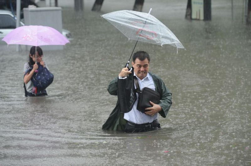 People hold umbrellas as they walk past a flooded street in Taiyuan, Shanxi Province, China, July 19, 2016. China Daily/via REUTERS ATTENTION EDITORS - THIS IMAGE WAS PROVIDED BY A THIRD PARTY. EDITORIAL USE ONLY. CHINA OUT. TPX IMAGES OF THE DAY - RTSIO11